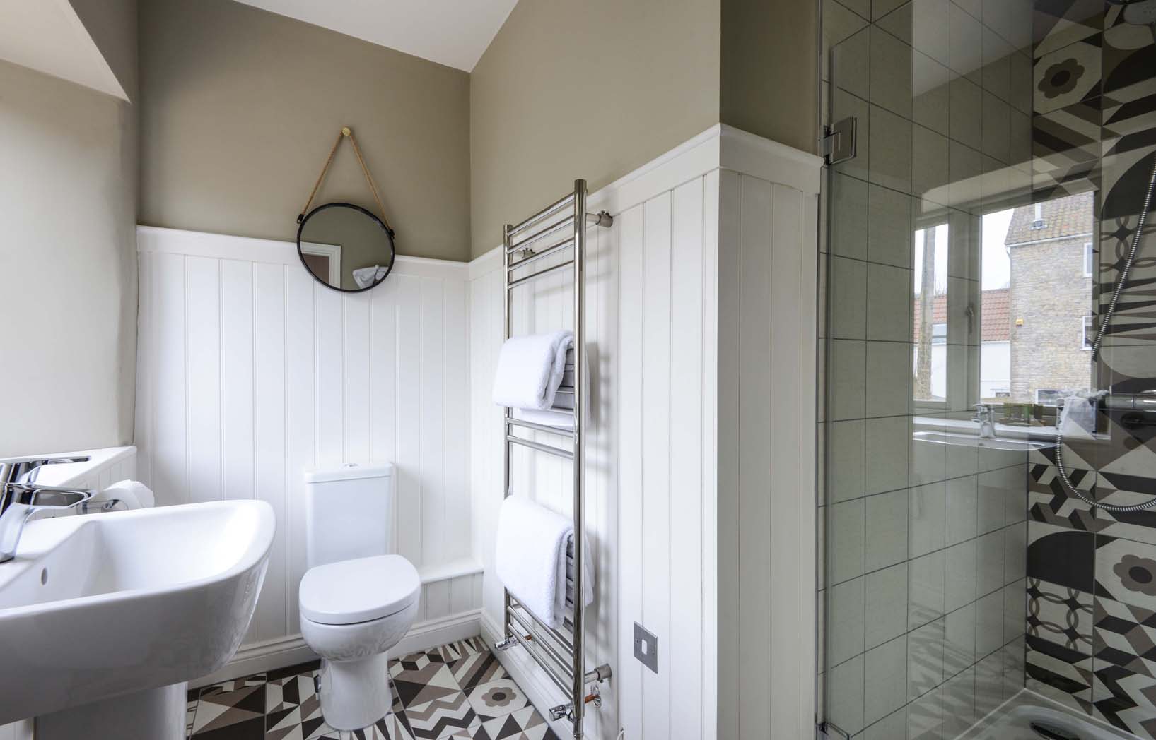 Butter Wells - Walk in shower with wooden panels, geometric tiled floor and heated towel rack