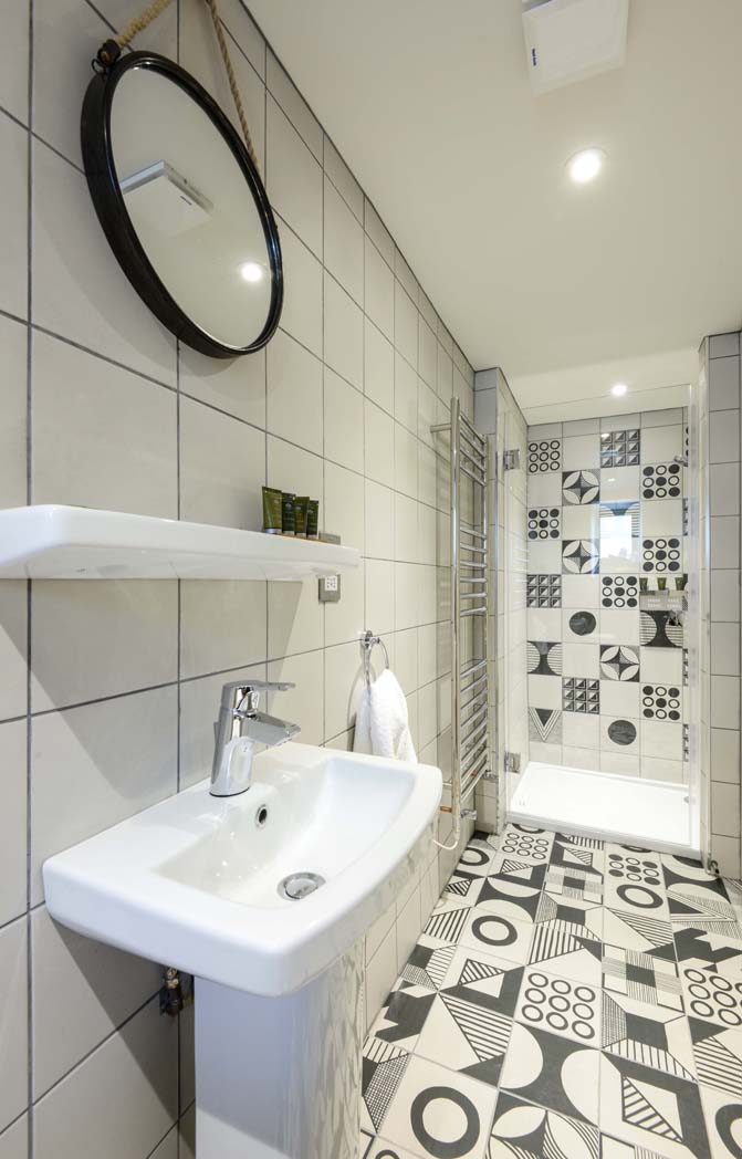 North Field - Bathroom of the family room with black and white tiles, a shower and basin.